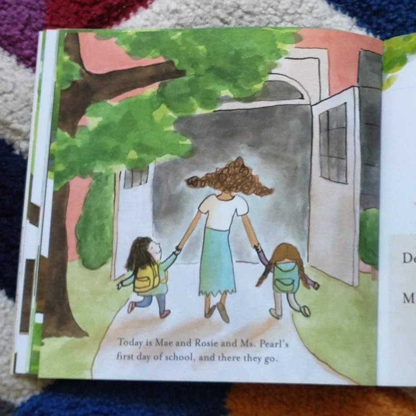 Two little girls and their teacher go happily into school to start their first day